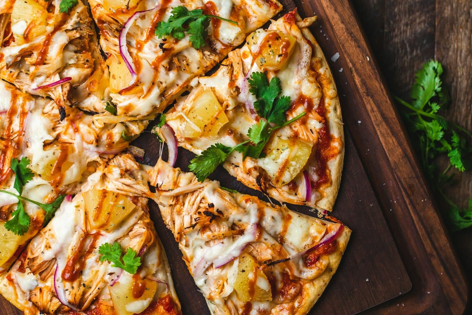 A whole pizza with tomato, basil, and olives on a wooden board